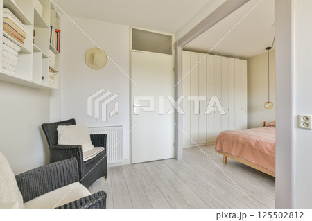 A bright, modern bedroom featuring minimal decor, a cozy bed, stylish furniture, and an inviting atmosphere ideal for relaxation. 125502812