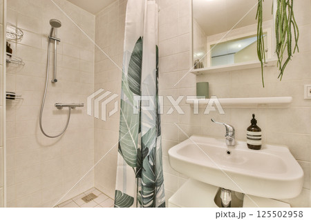 A stylish bathroom featuring a tropical-themed shower curtain and sleek fixtures, showcasing a blend of functionality and contemporary design. 125502958
