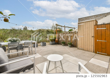 A beautifully arranged outdoor patio featuring comfortable seating, potted plants, and a rustic wooden fence, perfect for relaxation and gatherings. 125502963