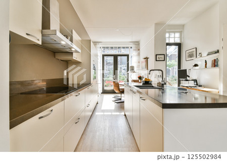 A sleek and modern kitchen featuring minimalist cabinetry, ample natural light, and elegant finishes, creating an inviting culinary space. 125502984