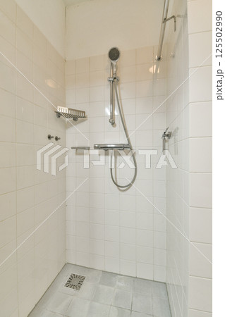 A contemporary shower stall featuring clean, white tiled walls and a sleek shower head. The design emphasizes simplicity and functionality. A contemporary shower stall featuring clean, white tiled walls and a sleek shower head. The design emphasizes simplicity and functionality. 125502990