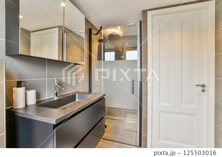 A contemporary bathroom featuring a walk-in shower, stylish sink, and elegant lighting, showcasing modern design elements and functionality. A contemporary bathroom featuring a walk-in shower, stylish sink, and elegant lighting, showcasing modern design elements and functionality. 125503016