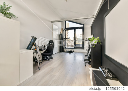 A sleek modern gym setup featuring exercise equipment, natural light, and contemporary aesthetic elements. Perfect for fitness enthusiasts and home decor inspiration. 125503042