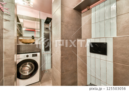 A stylish laundry room featuring sleek designs, neutral tones, and modern appliances, maximizing functionality in a compact space. 125503056