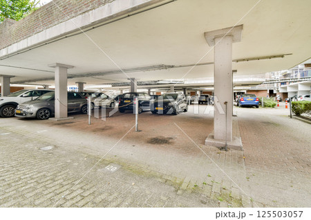 A spacious multi-level parking garage showcasing several parked cars in a well-lit area. The architectural design combines functionality with an organized layout. 125503057