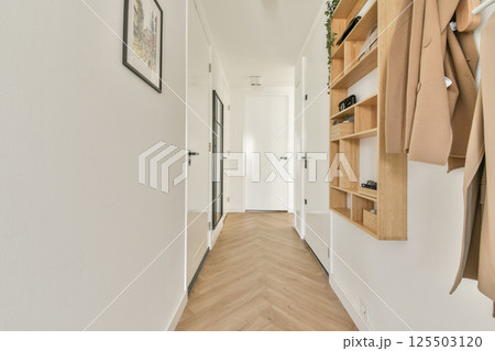 A sleek, modern hallway featuring light-colored walls, wooden flooring, and minimalist decor with stylish shelving. Perfect for contemporary home aesthetics. A sleek, modern hallway featuring light-colored walls, wooden flooring, and minimalist decor with stylish shelving. Perfect for contemporary home aesthetics. 125503120