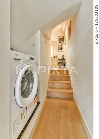 A clean and well-organized laundry area featuring a washing machine and a staircase, enhancing the home's functionality and aesthetics. A clean and well-organized laundry area featuring a washing machine and a staircase, enhancing the home's functionality and aesthetics. 125503185