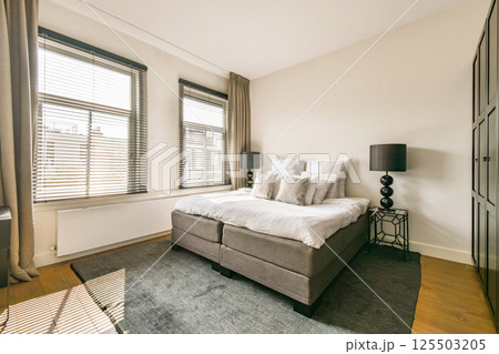 A spacious bedroom featuring large windows, soft lighting, and a neutral color palette. The stylish decor enhances the calming atmosphere. A spacious bedroom featuring large windows, soft lighting, and a neutral color palette. The stylish decor enhances the calming atmosphere. 125503205