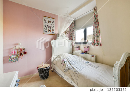 A beautifully decorated bedroom showcasing soft pastel colors, floral curtains, and butterfly art, creating a warm and inviting atmosphere. 125503383