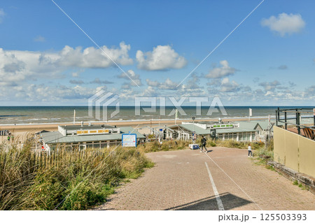 A scenic view of a coastal path lined with grass leading towards the beach, showcasing a clear sky and calm sea in the background. A scenic view of a coastal path lined with grass leading towards the beach, showcasing a clear sky and calm sea in the background. 125503393