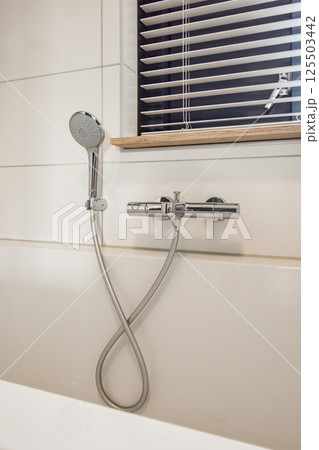 A sleek and contemporary shower fixture stands out against a clean tiled wall, featuring minimalistic design and elegant chrome detailing. A sleek and contemporary shower fixture stands out against a clean tiled wall, featuring minimalistic design and elegant chrome detailing. 125503442