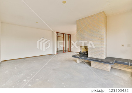 A lightly furnished living room showcases a modern minimalist aesthetic, featuring a brick fireplace and neutral-toned walls. Ideal for contemporary home designs. A lightly furnished living room showcases a modern minimalist aesthetic, featuring a brick fireplace and neutral-toned walls. Ideal for contemporary home designs. 125503482