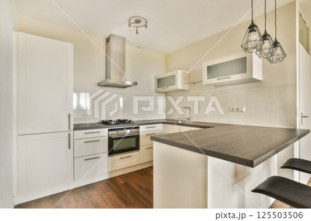 A sleek and stylish modern kitchen featuring contemporary cabinetry, a central island, and sophisticated appliances, ideal for cooking and entertaining. 125503506