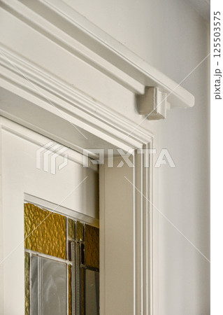 Intricate design of a door frame featuring beautiful glass accents. The light plays through the textures, enhancing the architectural elegance. 125503575