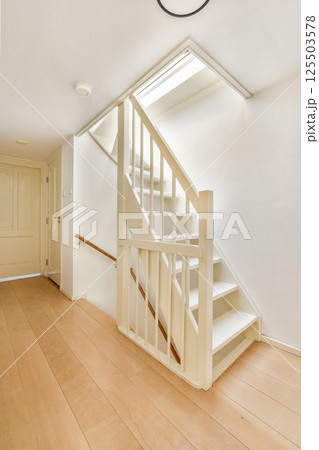A sleek, modern staircase design with white walls and wooden flooring, enhancing the aesthetic of a contemporary home interior. 125503578