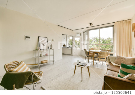 A spacious and contemporary living area featuring large windows, stylish furniture, and minimalistic decor, creating an inviting atmosphere with natural light. A spacious and contemporary living area featuring large windows, stylish furniture, and minimalistic decor, creating an inviting atmosphere with natural light. 125503641