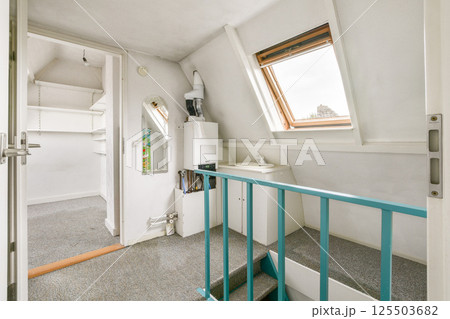 A stylish interior featuring neutral tones, with an inviting staircase and a window allowing natural light. Perfect for a cozy residential vibe. 125503682