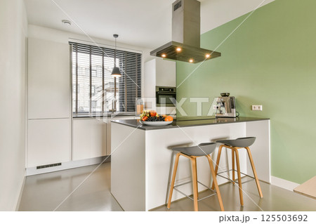 A contemporary kitchen featuring sleek design elements, a green accent wall, a stylish kitchen island, and modern appliances, creating a vibrant cooking space. A contemporary kitchen featuring sleek design elements, a green accent wall, a stylish kitchen island, and modern appliances, creating a vibrant cooking space. 125503692