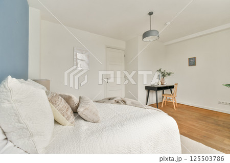 A warm and inviting minimalist bedroom featuring a neatly made bed, decorative pillows, and a small workspace with a chair and table, emphasizing a serene atmosphere. A warm and inviting minimalist bedroom featuring a neatly made bed, decorative pillows, and a small workspace with a chair and table, emphasizing a serene atmosphere. 125503786