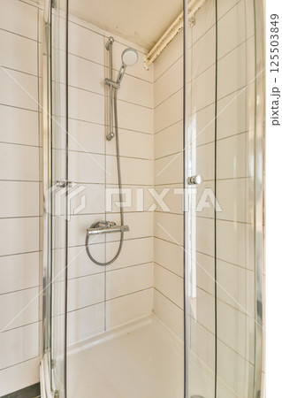 A contemporary shower stall featuring glass doors, sleek fixtures, and clean lines, set in a bright and minimalist bathroom environment. 125503849
