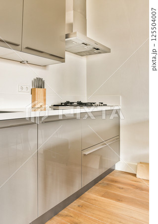 Sleek modern kitchen showcasing minimalistic cabinetry, a countertop, and a neatly organized cooking area with essential utensils. 125504007