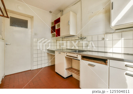 A clean and simple kitchen featuring white tiles and minimalist cabinetry. The warm tones create a cozy atmosphere, perfect for cooking. A clean and simple kitchen featuring white tiles and minimalist cabinetry. The warm tones create a cozy atmosphere, perfect for cooking. 125504011