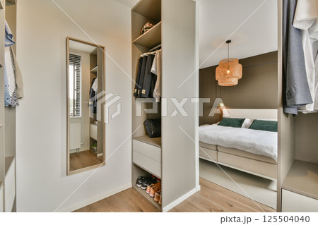 A contemporary bedroom featuring minimalist design, a cozy atmosphere, and stylish furniture. The wardrobe reflects modern aesthetics with smart storage solutions. A contemporary bedroom featuring minimalist design, a cozy atmosphere, and stylish furniture. The wardrobe reflects modern aesthetics with smart storage solutions. 125504040