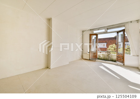 A sunlit, empty room featuring white walls and large windows that invite natural light, providing an airy and spacious atmosphere. A sunlit, empty room featuring white walls and large windows that invite natural light, providing an airy and spacious atmosphere. 125504109
