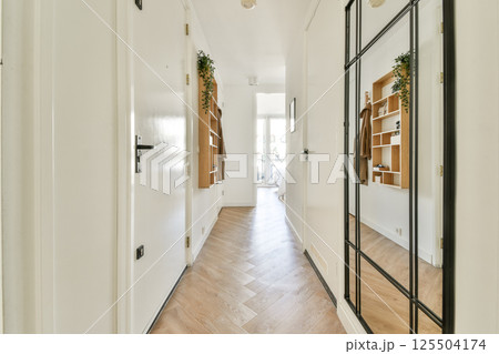 A contemporary hallway featuring sleek design, wooden flooring, and decorative shelving that creates a welcoming atmosphere. Natural light enhances the space. 125504174