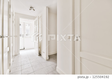 an empty hallway with white walls and tile flooring photo taken from the front door, looking towards the entrance an empty hallway with white walls and tile flooring photo taken from the front door, looking towards the entrance 125504192