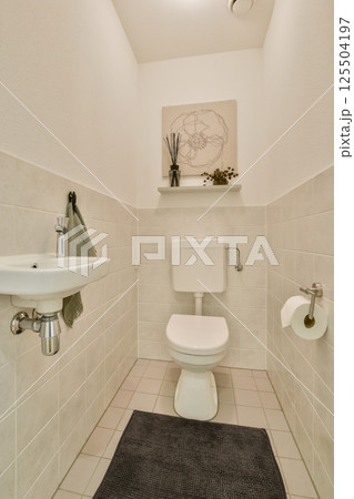 A clean and modern bathroom showcasing a white tiled interior, a sleek toilet, and minimalist decor elements for a fresh ambiance. A clean and modern bathroom showcasing a white tiled interior, a sleek toilet, and minimalist decor elements for a fresh ambiance. 125504197