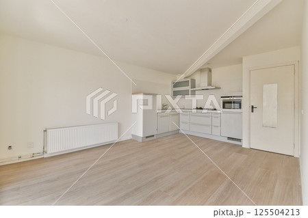 An empty, modern kitchen showcasing minimalist design with sleek white cabinetry and a light wooden floor. Ideal for contemporary living spaces. An empty, modern kitchen showcasing minimalist design with sleek white cabinetry and a light wooden floor. Ideal for contemporary living spaces. 125504213