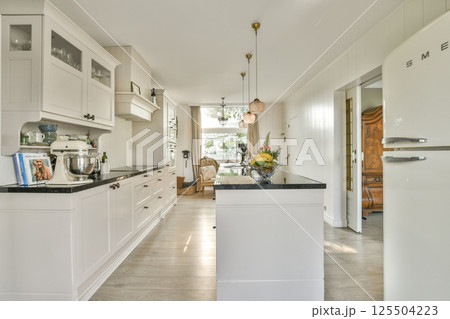 A bright and modern minimalist kitchen featuring sleek cabinetry, stylish decor, and elegant lighting. The space invites a sense of warmth and functionality. A bright and modern minimalist kitchen featuring sleek cabinetry, stylish decor, and elegant lighting. The space invites a sense of warmth and functionality. 125504223
