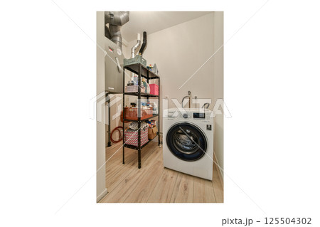 A clean and organized laundry space featuring a front-loading washer, stylish shelving for storage, and a minimalist design perfectly for modern homes. A clean and organized laundry space featuring a front-loading washer, stylish shelving for storage, and a minimalist design perfectly for modern homes. 125504302