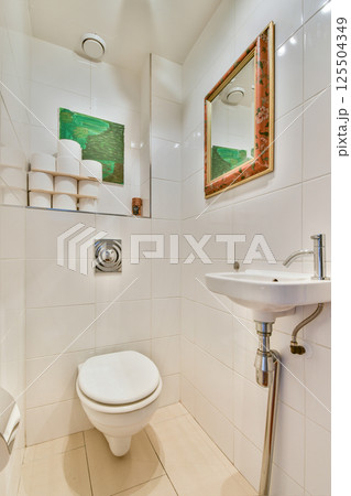 A bright and stylish bathroom featuring a modern toilet, sleek sink, and artistic wall decor, creating a welcoming atmosphere. A bright and stylish bathroom featuring a modern toilet, sleek sink, and artistic wall decor, creating a welcoming atmosphere. 125504349