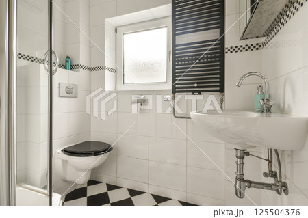 Contemporary bathroom showcasing sleek fixtures, black and white tile flooring, and stylish lighting, ideal for modern home aesthetics. 125504376