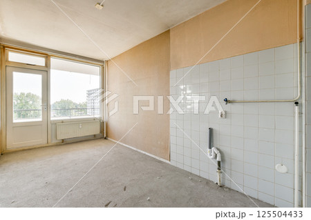 An unfurnished room featuring large windows that let in ample natural light. The minimalistic design highlights the spaciousness of the area. 125504433