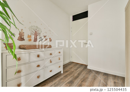 A bright and inviting hallway featuring a stylish dresser, nature-inspired wall art, and wooden flooring, creating a warm atmosphere in the space. 125504435