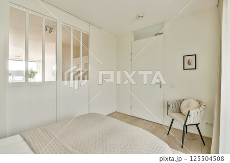 A contemporary bedroom featuring a stylish bed, soft textures, and minimalistic design elements. The space promotes tranquility and simplicity. 125504508