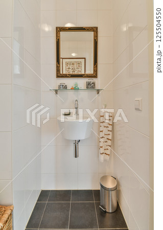 A minimalist bathroom showcasing sleek white tiles, a stylish mirror, and contemporary fixtures, creating an elegant and fresh atmosphere. 125504550