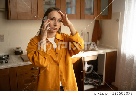 Woman seeks help for leaky sink in cozy kitchen during a busy morning Woman seeks help for leaky sink in cozy kitchen during a busy morning 125505073