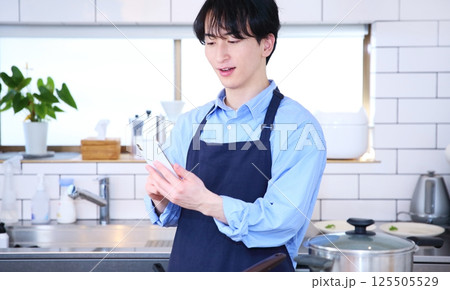 キッチン　スマホを見て考える男性のイメージ 125505529