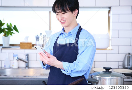 キッチン　スマホを見て考える男性のイメージ 125505530