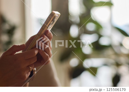 A person is comfortably using their smartphone while sitting in a cozy, relaxed environment 125506170