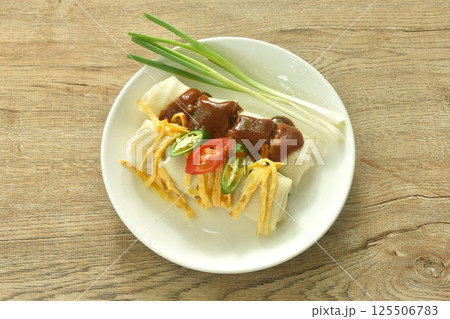 fresh Chinese spring roll made from flour wrapped tofu and pork with bean sprout dressing sweet red gravy sauce on plate    125506783