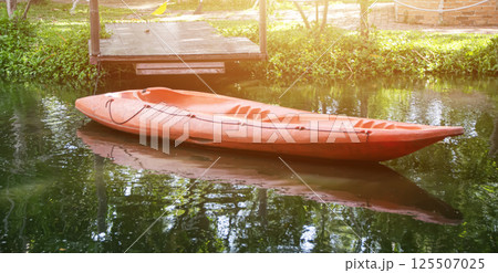 An orange kayak is parked at a dock on the lake. An orange kayak is parked at a dock on the lake. 125507025