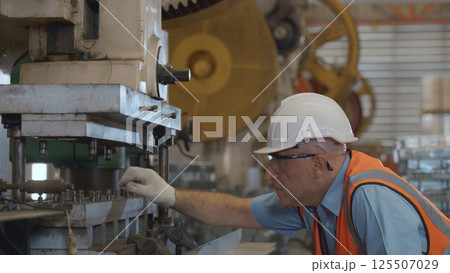Engineer or operator wearing a safety suit working bending metal sheet by sheet press bending machine in workshop, Worker in factory at metal folding machine putting work piece at factory industry Engineer or operator wearing a safety suit working bending metal sheet by sheet press bending machine in workshop, Worker in factory at metal folding machine putting work piece at factory industry 125507029