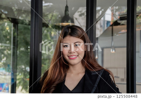 A cheerful young woman smiles confidently in a modern workspace, exuding positivity and professionalism. A cheerful young woman smiles confidently in a modern workspace, exuding positivity and professionalism. 125508448