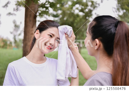 Two women enjoying time outdoors, showcasing friendship and support in a healthy lifestyle setting. 125508476