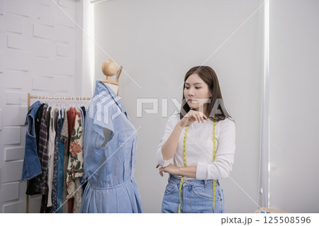 A stylish woman thoughtfully examines a dress on a mannequin in a modern fashion studio. A stylish woman thoughtfully examines a dress on a mannequin in a modern fashion studio. 125508596